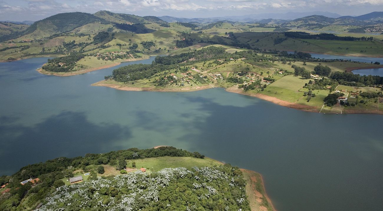 Aerial view of a large reservoir amidst sweeping green hills.