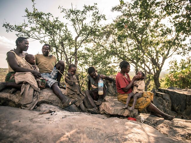 Moshi Nakunda's family sits on boulders in the shade