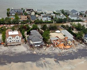 Coastal community post-Sandy with sand-covered, damaged houses.