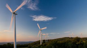 Wind turbines on rolling hills and blue skies.