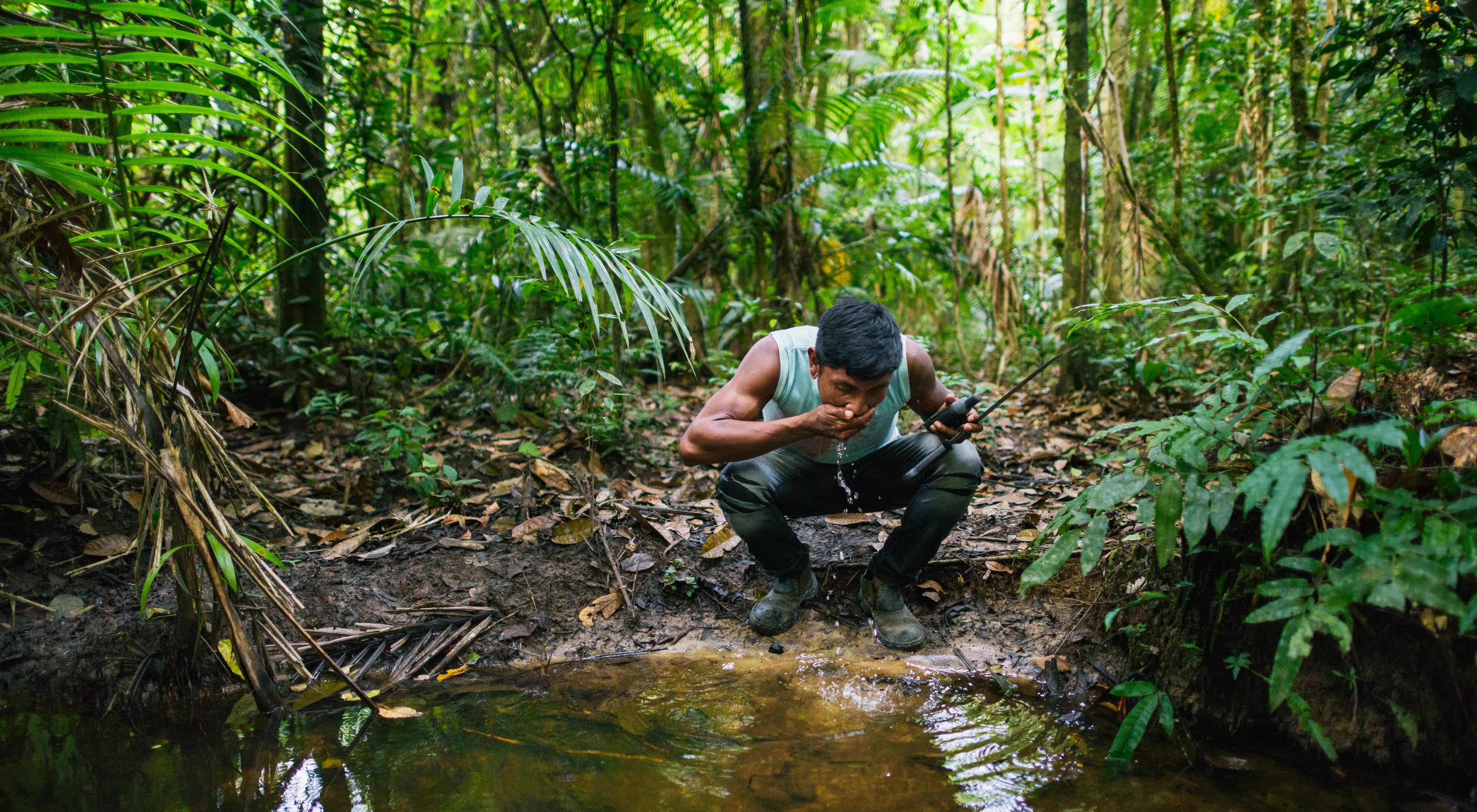 A surveyor stops for a drink of water in a forest near the Pot-Kro Village in the Brazilian Amazon