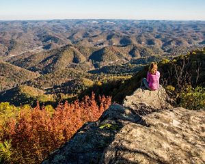A hiker rests on a rock to look at the panoramic view.