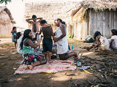 Mujeres xikrin pintando a niños en la comunidad
