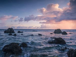 A view arcoss the rocky inner reef towards an evening sky filled with rainclouds and golden light near the village of Utwe on the Island of Kosrae, Micronesia. 