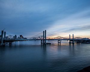 A bridge spanning a river with a city in the background.