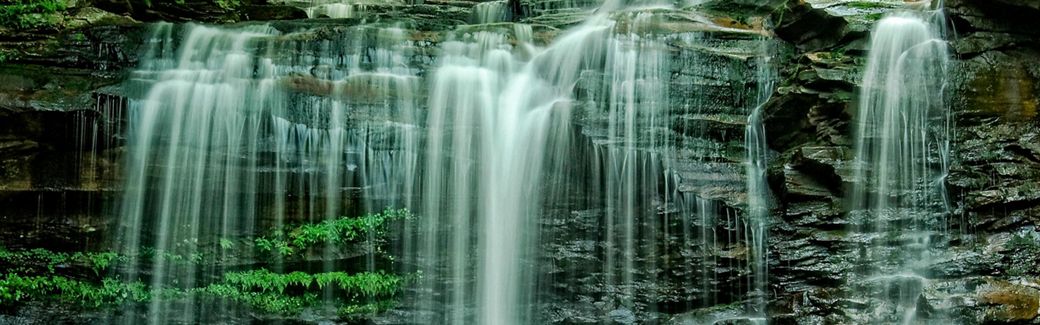 White water cascades over vertical rocky falls into a pool below.