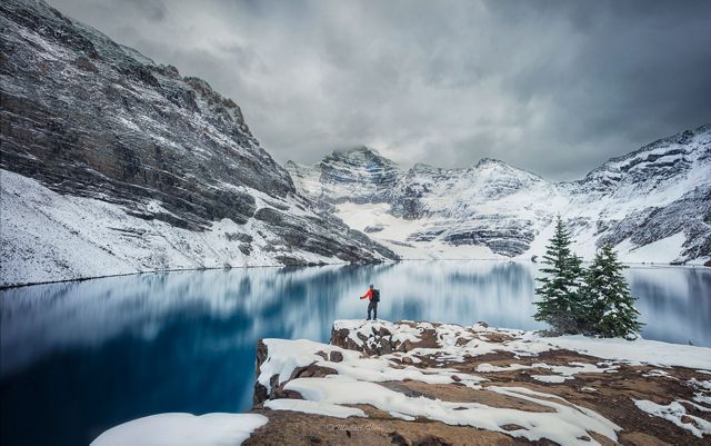 Lone hiker along snowy mountain lake