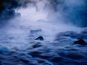 A long exposure of a misty river flowing over rocks