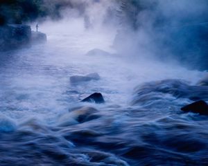 A long exposure of a misty river flowing over rocks