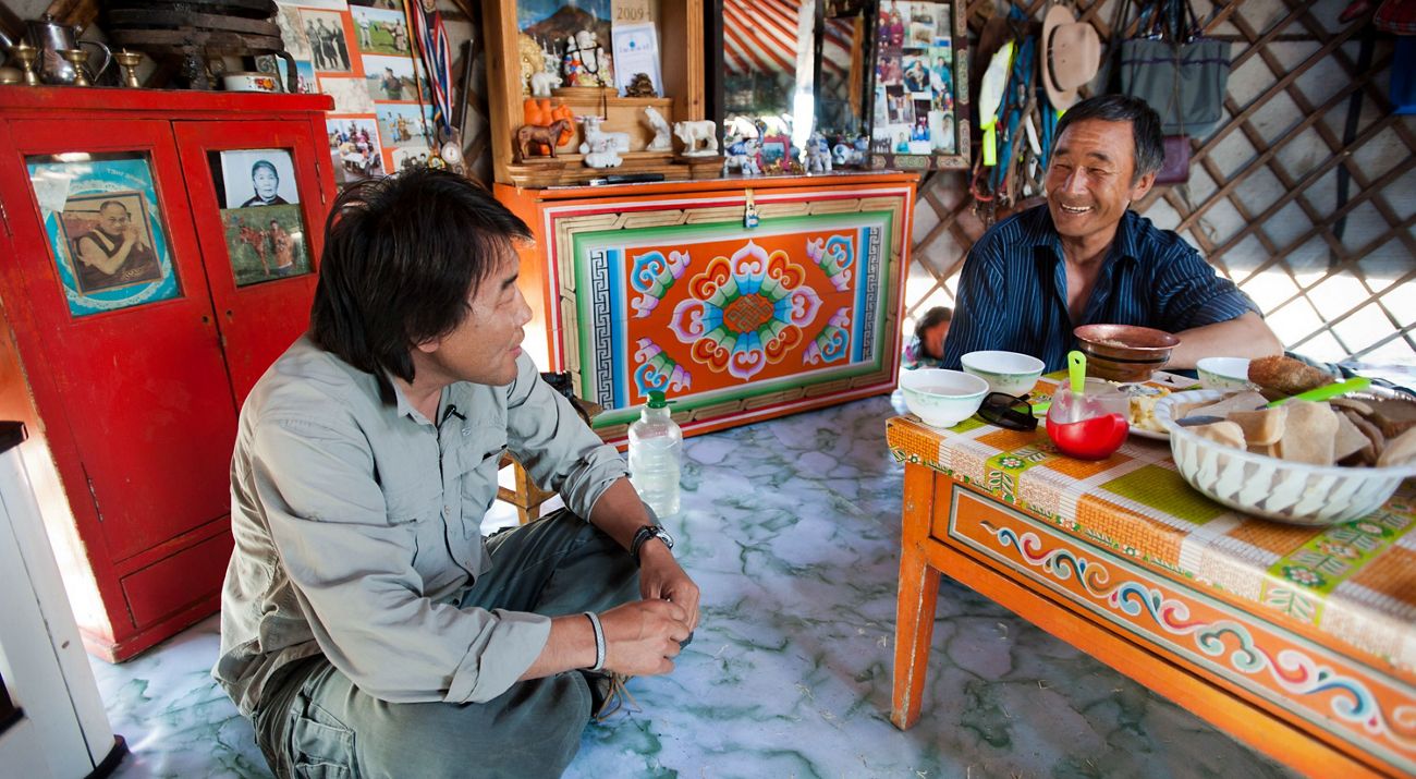 Gala Davaa, TNC Country Director of Mongolia, sits with a Mongolia herder over a meal.