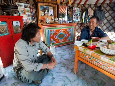 The Nature Conservancy's Galbadrakh (Gala) Davaa, (on left) Director of Conservation for the Mongolia Program with Otgonbaatar Tsog, a Mongolian herder and Conservancy partner in Mongolia, talking in Tsog's ger (ger, or yurt, is the traditional tent like home of nomadic Mongolian herders), in Mongolia. The rich natural resources of Mongolia’s steppes are attracting increased development, which is threatening the balance between humans and wildlife that has defined this country’s past. Through traditional land protection and cutting edge initiatives like Development by Design, the Conservancy is working to create a sustainable future that honors and preserves the sustainable culture of Mongolia’s grasslands.