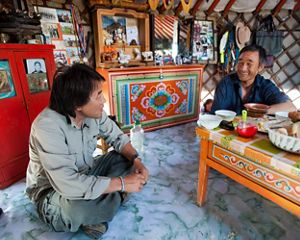 Gala Davaa, TNC Country Director of Mongolia, sits with a Mongolia herder over a meal.
