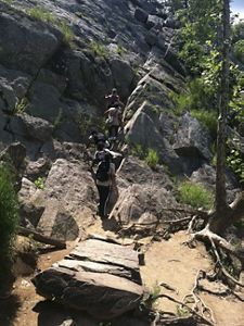 Hikers ascend a trail that includes a steep, rocky climb.