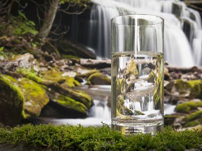 A glass of water positioned in front of a waterfall in West Virginia.