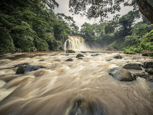 En la distancia se aprecia un cascada de agua cayendo sobre un río en una selva