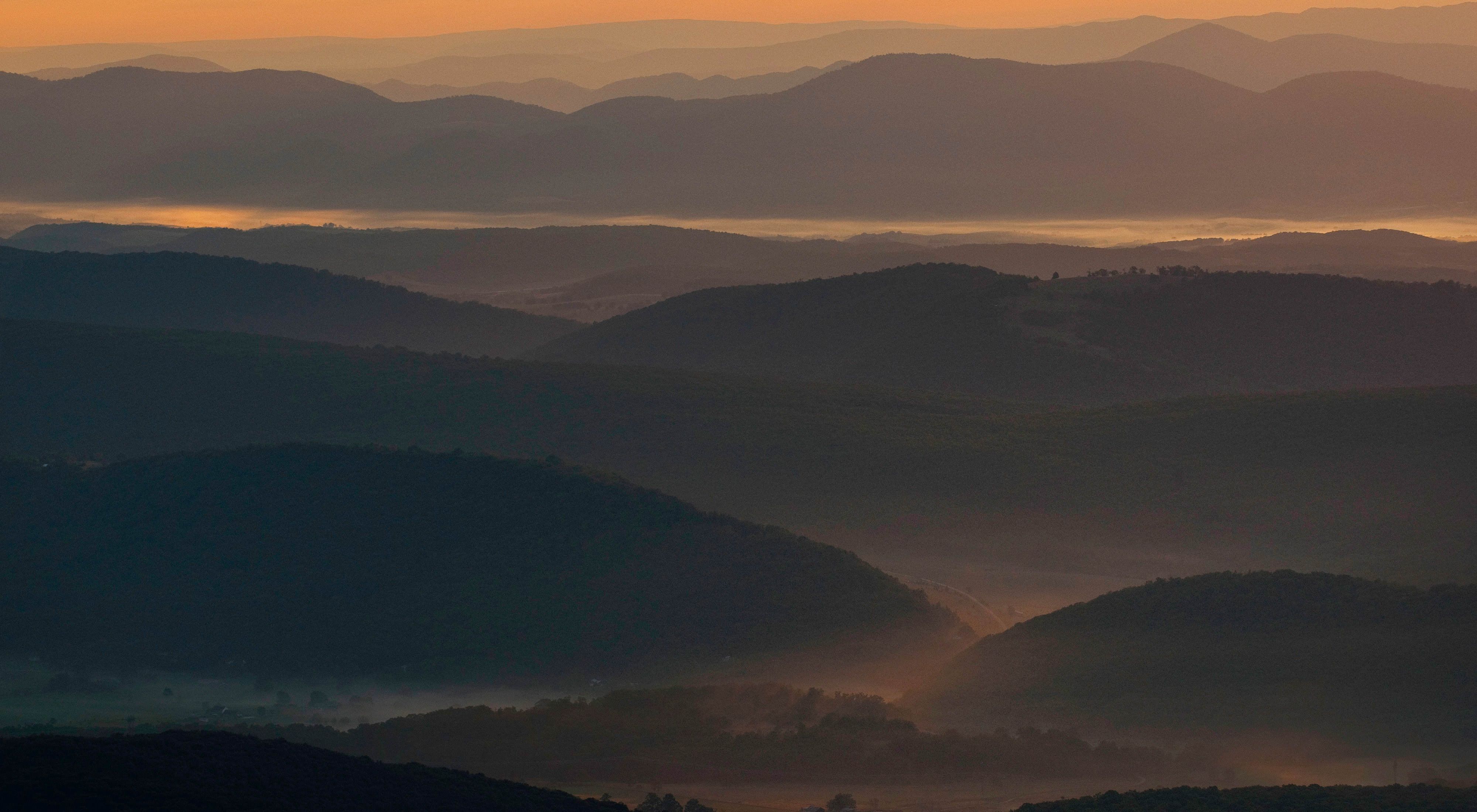 The rolling landscape of the Central Appalachians. The mountain ridges are silhouetted by the setting sun.