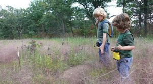 Two children standing in a grassland.