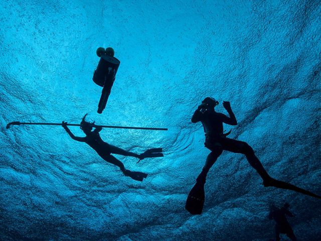 Two students swim around a floating salinity and tempurature probe as part of a water-monitoring project at Palmyra Atoll.