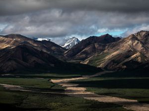 Dramatic view of a mountain pass under dark clouds in Alaska.