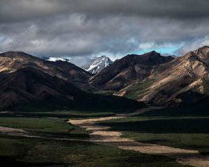 Dramatic view of a mountain pass under dark clouds in Alaska.