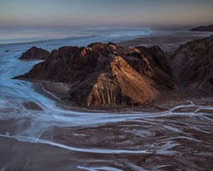 aerial of a drying river bed surrounded by mountains.