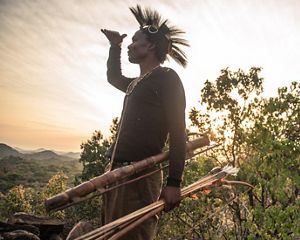 A hunter surveys a valley in Tanzania, looking for game