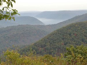 An overlook viewing of forested covered hills with mist rising from the valleys.