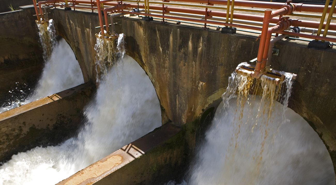 Water pours through openings in concrete structure.