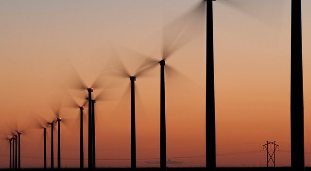 Photo of wind turbines on a prairie at sunset.