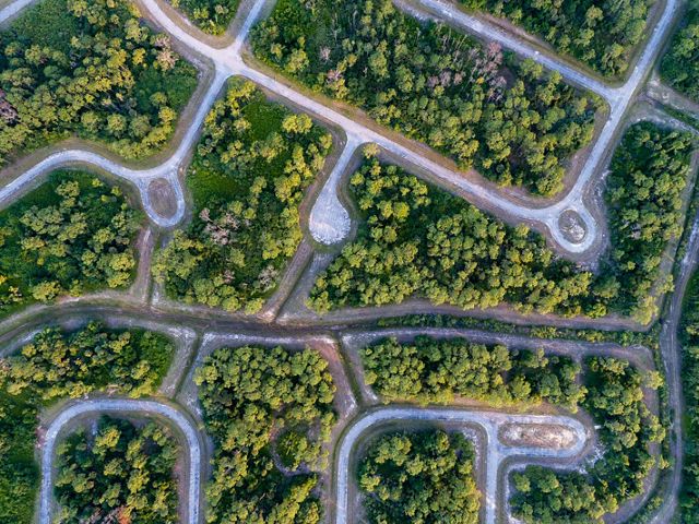 aerial of roads and cul de sacs from a foreclosed development through a forest in Florida