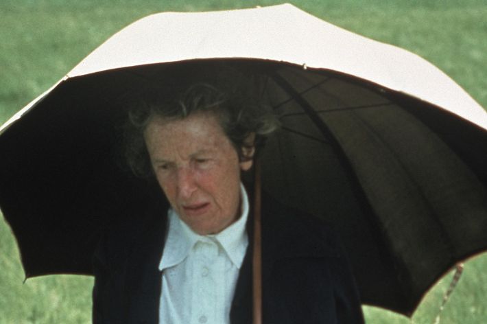 A woman wearing a black sweater holds a white umbrella.