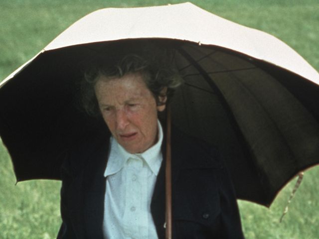 A woman wearing a black sweater holds a white umbrella.
