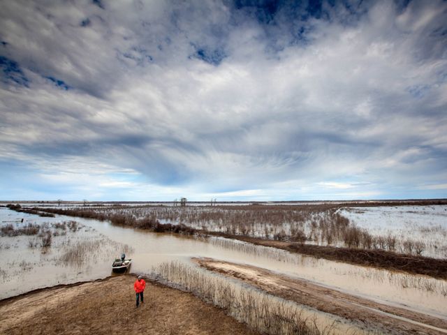 Floodplains stretch out on a wintery day with a boater about to board his little skiff.