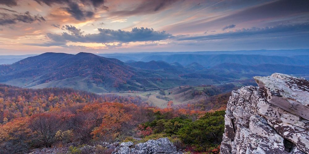 sweeping view of tree-covered mountains with autumn leaves changing