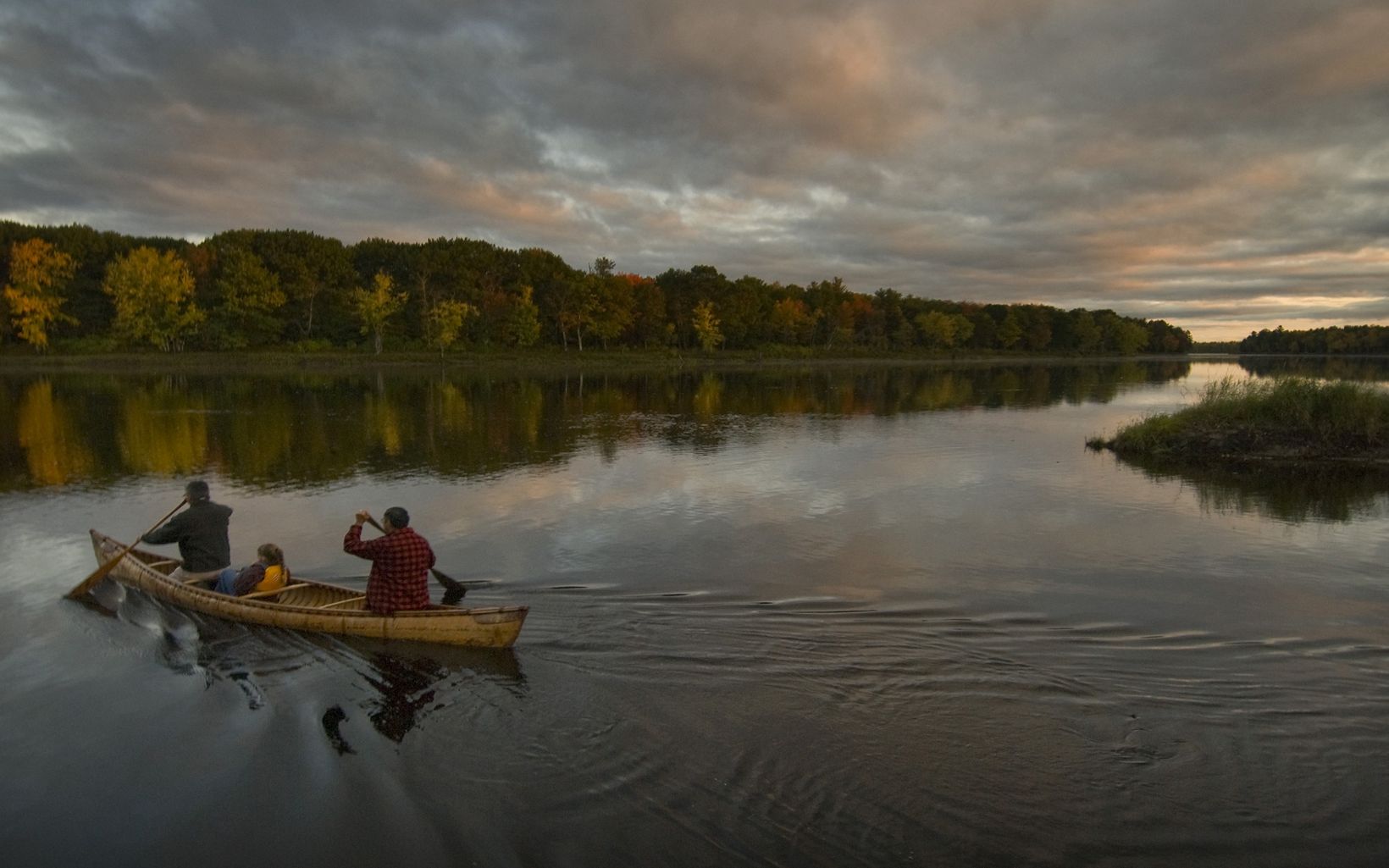 Photo of two adults and a child paddling on the Penobscot River.