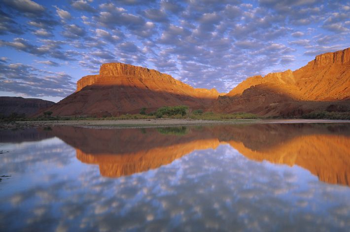 Montanas rojizas y reflejos de cielo azul en el rio Colorado en Utah.