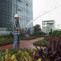 An employee waters the rooftop garden on the Tencent Binhai towers in Shenzhen, China. November 2017. Environmental features of the Tencent Binhai towers in Shenzhen, China include rooftop gardens on the three skybridges, permeable surfaces to slow rainwater on the two towers' topmost roof and many of the landings and ground level, solar panels and 'smart rooms' that adjust temperature based on how many people are in them. TNC's Build Healthy Cities Program. 