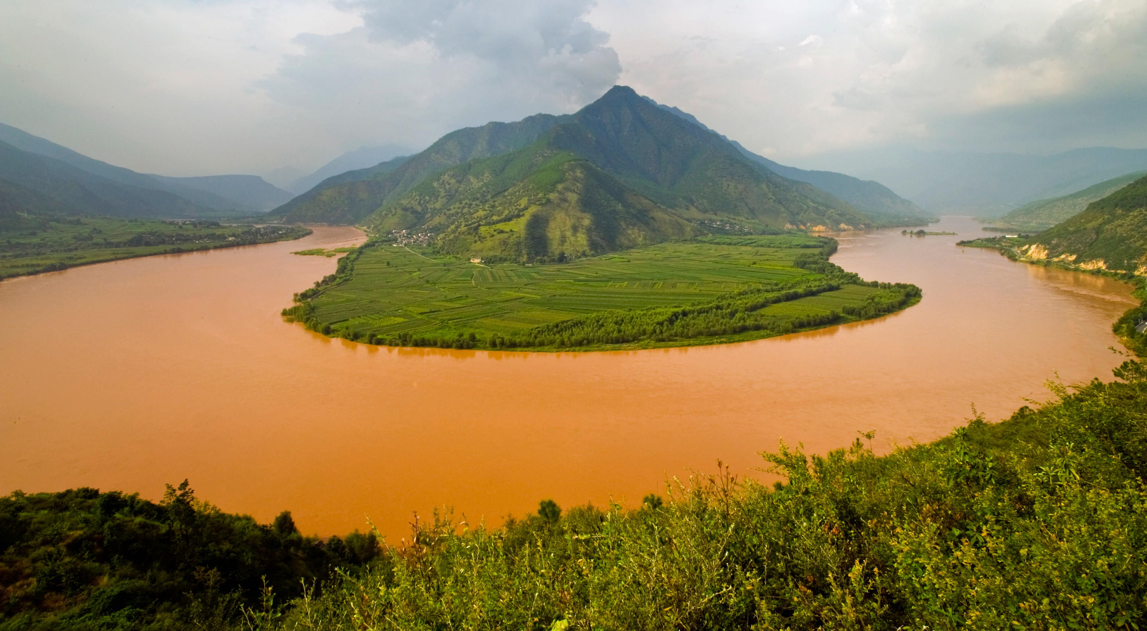 Heavy rains turn the river a muddy-brown as viewed above a bend in Yunnan province, southwestern China.