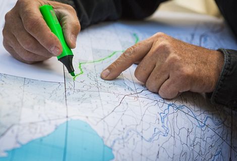 Hands and a highlighter outlining a path on a map.