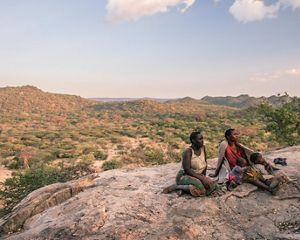 Two women sitting on an outcrop with a beautiful landscape stretching behind them.