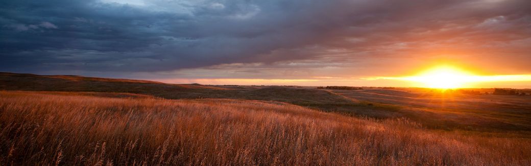Sunset over grassy hills.