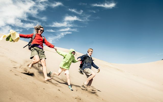 A family runs down the dunes at Great Sand Dunes National Park