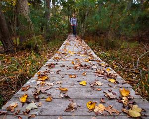 Bekah Herndon hikes amidst colorful fallen leaves on a boardwalk along the Blueberry Ridge Trail in the Nags Head Woods Preserve © Ben Herndon