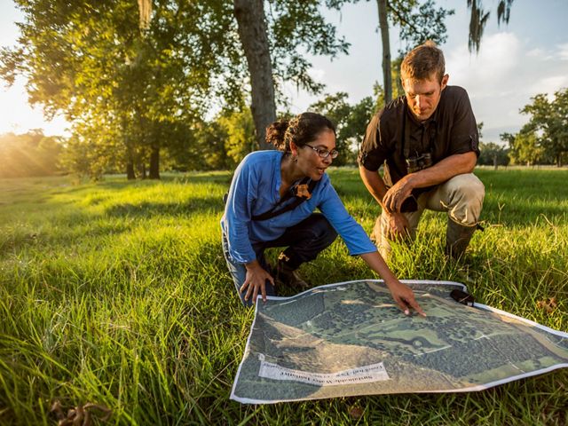 Two people in a field studying a topographical map.