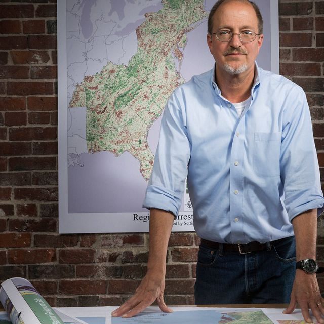 Photo of Dr. Mark Anderson, standing in front of maps.