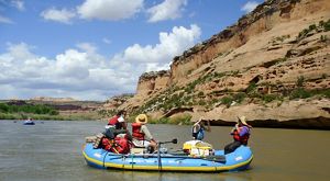 A group of people in a river on a raft flowing through a canyon.