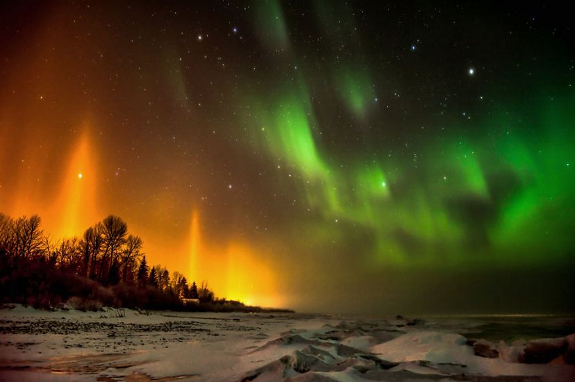 Las auroras boreales refulgen en naranja y verde.