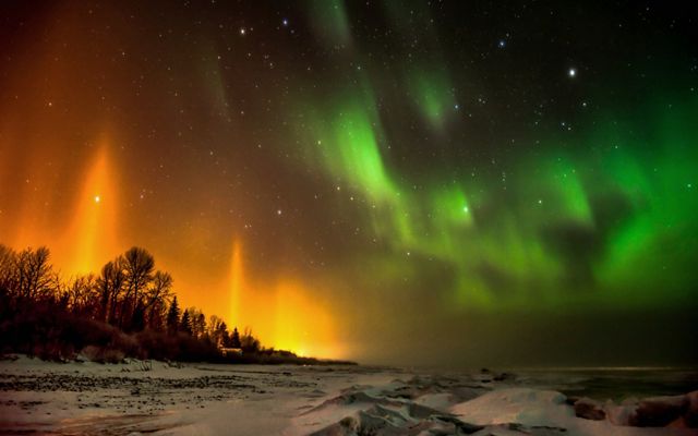 Las auroras boreales refulgen en naranja y verde.