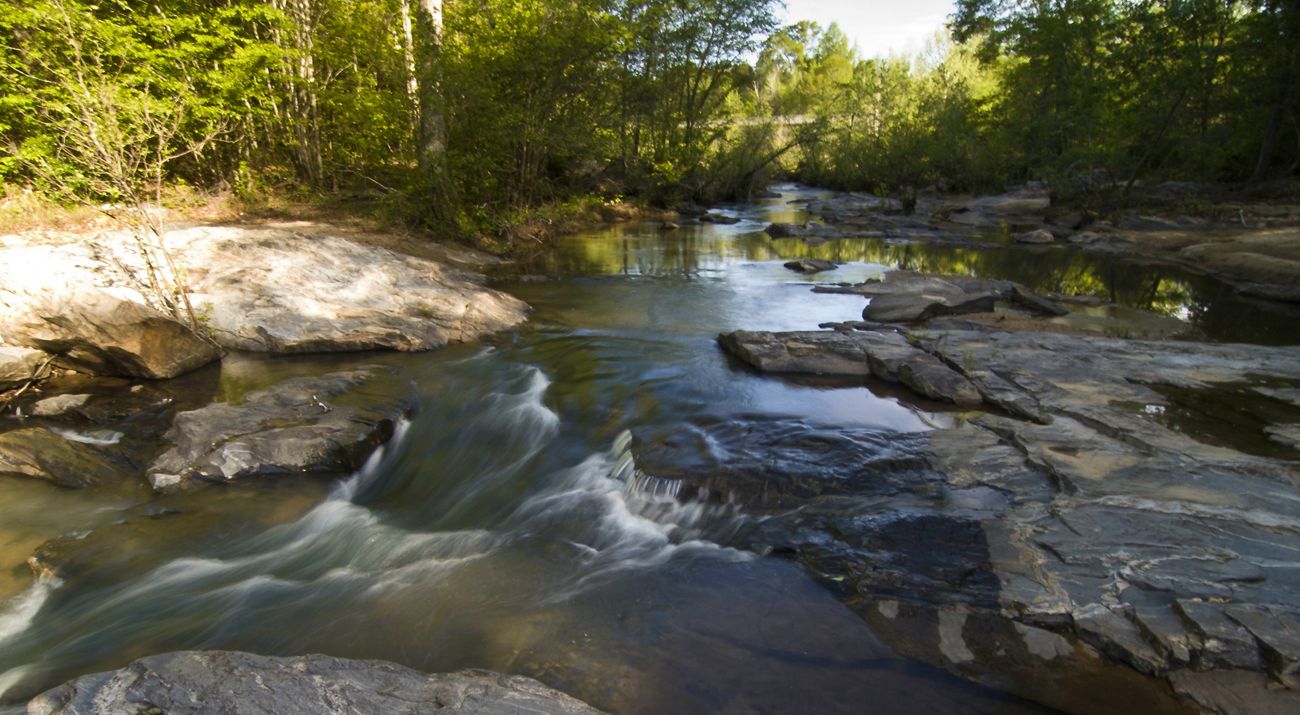 Water rushes over rocks in a narrow river channel.