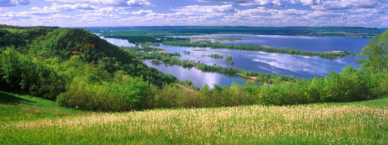 A wide angle view of the Mississippi River captured from a green field on a hill in Onalaska, Wisconsin.